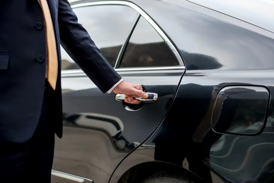 Conductor profesional abriendo la puerta de un vehículo ejecutivo
